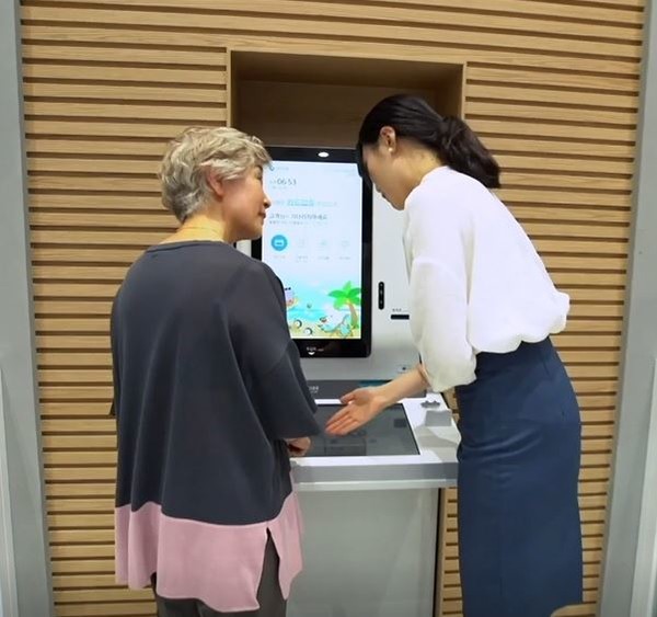 서울시 중구에 위치한 신한은행 디지로그 브랜치 서소문지점에서 컨시어지 직원이 시니어 고객에게 카드 업무 전용 디지털 키오스크 사용법을 안내하는 모습.(신한은행 제공)