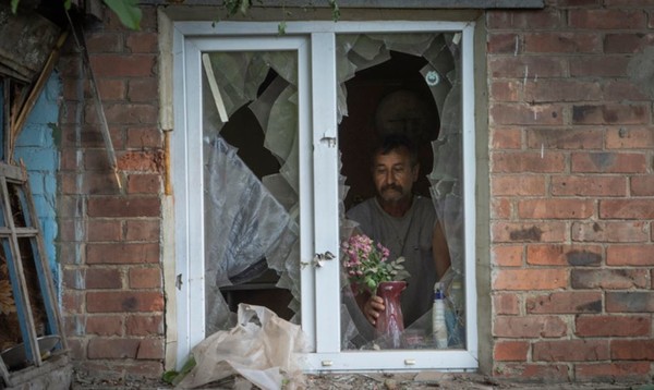 26일(현지시간) 우크라이나 도네츠크주 바흐무트에서 한 주민이 러시아군의 포격으로 파괴된 자기 집 창문에 화병을 놓고 있다.(뉴시스 제공)