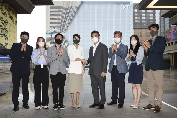 KT 전략기획실장 김채희 전무(왼쪽 네번째)와 서울시 주용태 문화본부장(오른쪽 네번째)이 양측 관계자들과 함께 광화문 West 사옥 공사 가림막을 배경으로 세종문화회관 중앙계단에서 업무협약 체결 기념 촬영하는 장면 (KT 제공)