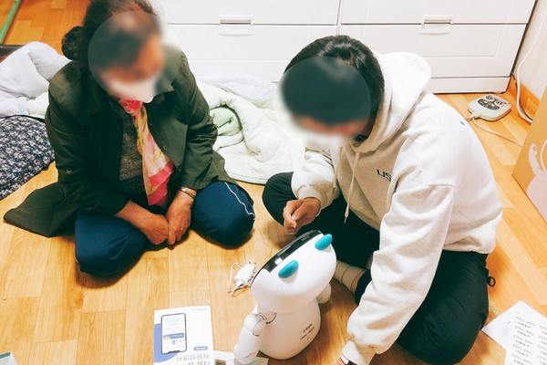 복원기금 지원을 받은 스타트업 원더풀플랫폼 직원이 자사가 만든 건강관리 기구 사용법을 독거 노인에게 설명하고 있다. [사진=복권기금]