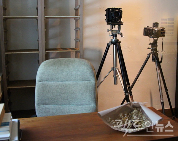 전시장 출입구 왼편에는 고 김영갑 작가가 생전 사용하던 의자와 카메라 등이 있고, 전시장 안에는 고 김영갑 작가의 일상을 담은 영상이 관람객을 맞는다. [사진=정수남 기자]