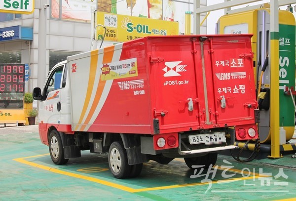 (위부터)우정사업본부 집배원이 우편물 수거 전기자동차를 타고 경기 수원시 매송고색로에서 우편물을 수거하고 있다. 인근 서부로에서 우본 택배 차량이 경유를 넣고 있다. [사진=정수남 기자]