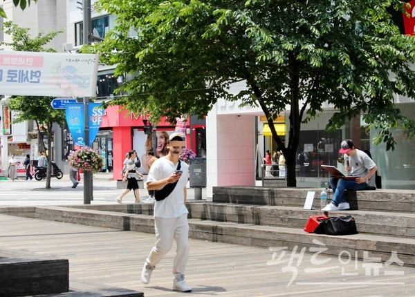 (위부터)연세로 가판 꽃집. 한 40대 여성이 꽃을 고르는 사이 꽃집 아저씨는 꽃다발을 만들고 있고, 인근 가로 공연장에서는 30대 남성이 휴대용 노래방 기기를 통해 노래하고 있다. [사진=정수남 기자]