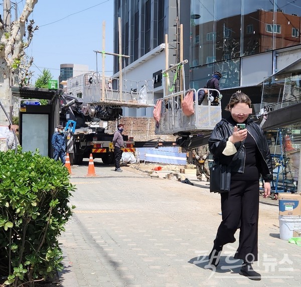 서울 마포구 월드컵북로 인도다. 신축 건물 공사장에서 대체 도로도 없이 인도를 무단으로 막았다. 20대 여성은 태평하게 스마트폰을 보면서 웃고 있다. [사진=정수남 기자]