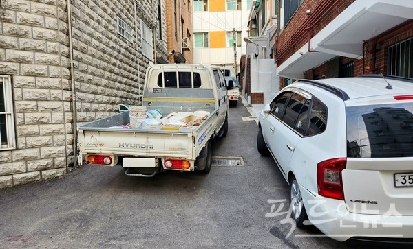 (위부터)아워홈 차량이 인도를 막고 식자재를 내리고 있다. 개인 차량도 골목을 막았다. 기업 차량이나 일반인 소유 차량이나 도긴개긴이다. [사진=정수남 기자]