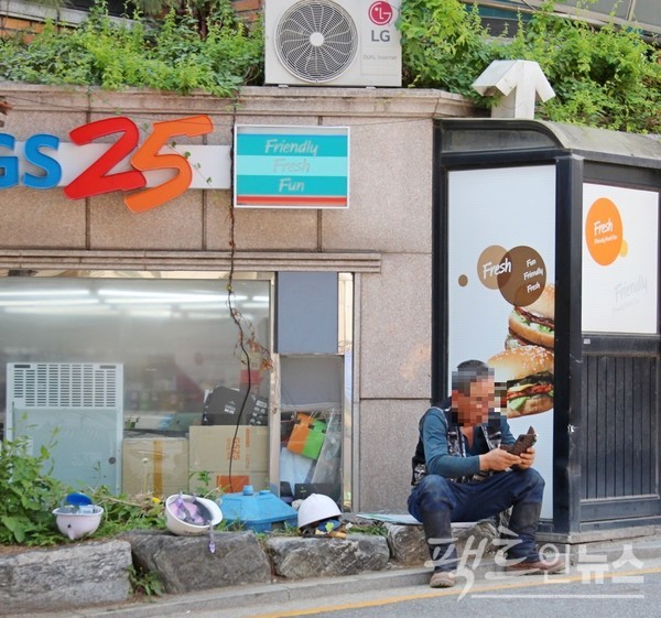 무더위가 시작했다. (위부터)KT의 현장 근로자가 나무 그늘에서, 공사장 인부가 편의점 앞에서 각각 스마트전화기를 보면서 휴식을 취하고 있다. 종전 GS그룹과 한집 살림을 한 LG 전자의 에어컨 실외기도 함께 잡았다. [사진=정수남 기자]