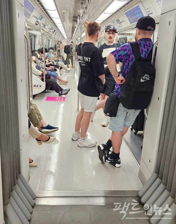 정오께 서울지하철이다, 객차 안이 뻥 뚫렸다. 카메라 앵글을 뒤로 가겨가자, 외국인 남성 셋이 통로를 막았다. [사진=정수남 기자]