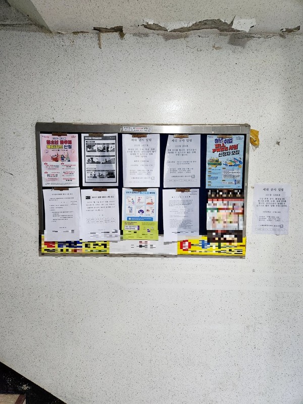 단지 일부 동의 출입구다. 장마로 비가 많이 내리면서 벽을 타고 물이 흘러 게시판을 적셨다. 천장도 누수로 페인트가 벗겨졌다. [사진=김모 씨]