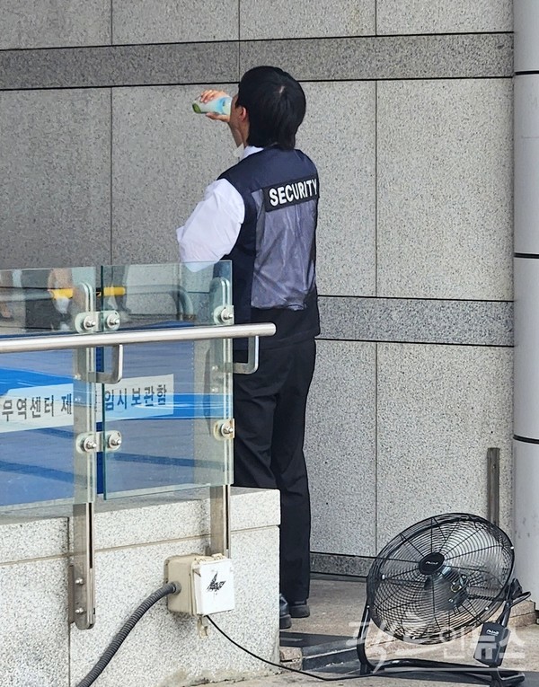 이로 인해 서울 삼성동 코엑스 보안요원이 전날 낮에 무더위를 식히기 위해 음료를 마시면서 선풍기를 가동하고 있다. [사진=정수남 기자]