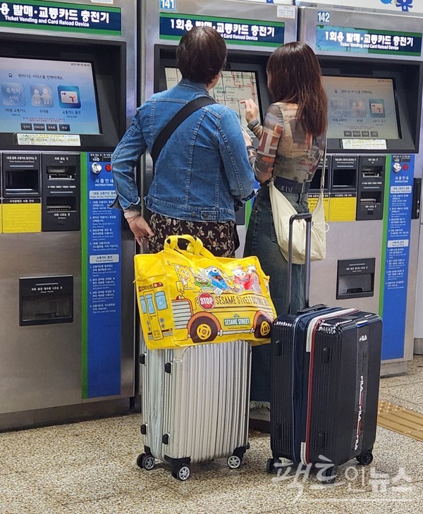 지하철 2호선과 공항철도 환승역인 홍대입구역에서 여행 가방을 든 모녀가 공항철도행 표를 구매하고 있다. [사진=정수남 기자]