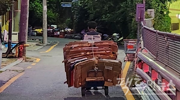 같은 날 새벽. 위 현수막 인근에서도 60대 노인이 페지 손수레를 끌고 가고 있다. [사진=정수남 기자]