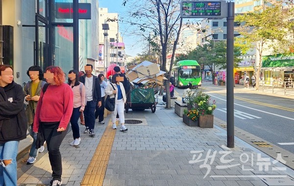 폐지와 고물 등을 수집하는 한 노인이 손수레와 폐지 등으로 인도를 막았다. 노인은 상대적으로 고부가가치인 알루미늄 고물 파이프에서 비닐을 벗기는데 몰두하고 있고, 행인은 어렵사리 인도를 걸어가고 있다. [사진=정수남 기자]