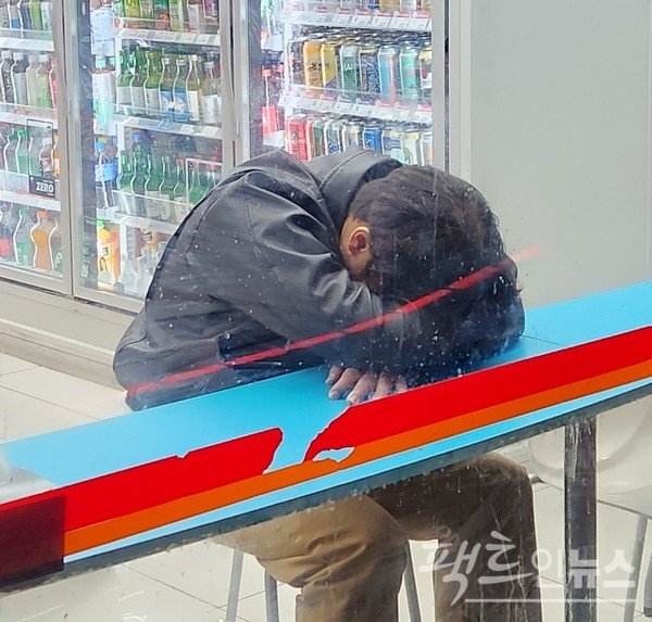 한 20대 남성 취객이 계단에서 잠이 들었다. 반면, 다른 20대 남성은 편의점에서 수마에 빠졌다. [사진=정수남 기자]