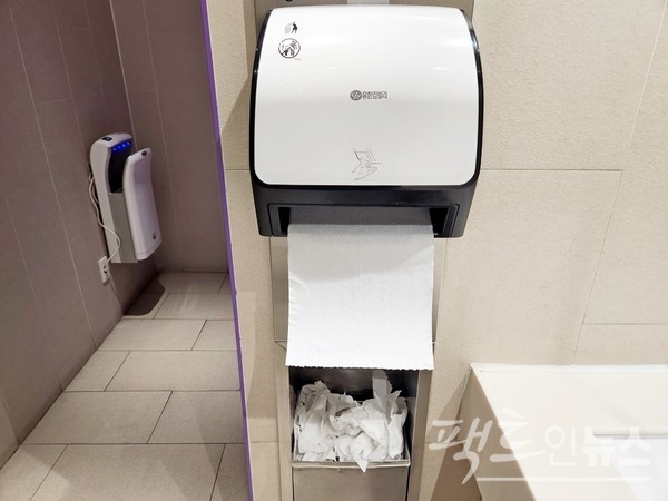 ’우리 강산 푸르게 푸르게‘를 기업가치로 하는 유한킴벌리가 올해 종이 수건 자동 지급기를 내놓고, 주요 건물 화장실에 이를 설치했다. 고객이 기기 아래에 손을 대면 종이 수건 한 장이 자동으로 나온다. 기존 수동형의 경우 한 번에 종이 수건 서너 장을 뽑아 쓰는 것을 방지하기 위한 것인데, 환경을 파괴하는 마찬가지. 왼쪽 벽에 있는 자동 손 건조기는 무용지물이다. [사진= 정수남 기자]