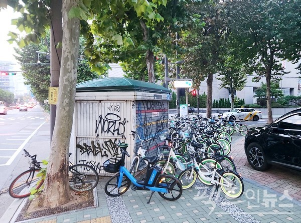 서울시가 운영하는 공유 자전거 따릉이가 서울 마포구 월드컵북로 인도를 점령했다. 아울러 마포구는 폐점 3년이 지난 가판 구두수선소(왼쪽)를 방치하고 있다. [사진= 정수남 기자]