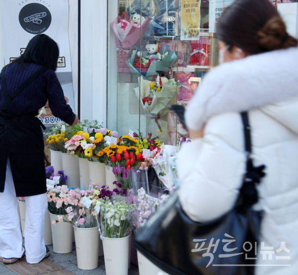 서울 서대문구 신촌로에 있는 꽃집이다. 봄을 맞는 꽃집 아가씨의 손이 분주하다. 꽃집을 지나는 20대 여성은 여전히 한겨울이다. [사진=정수남 기자]