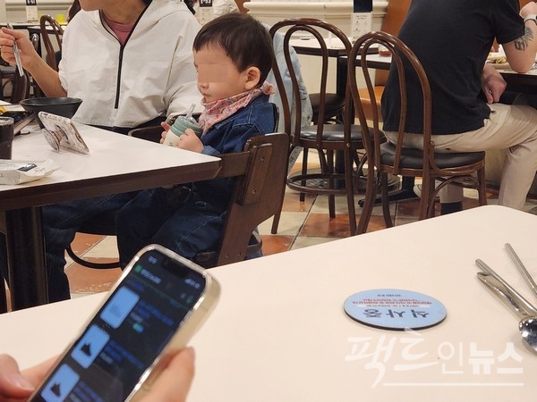 엄마가 음식을 가져오고 난 이후, 부모가 식사하는 사이에도 아이가 스마트 전화기를 뚫어지게 바라보고 있다. 옆 식탁에 앉은 중학생도 스마트 전화기를 열심히 들여다 보고 있다. [사진=정수남 기자]