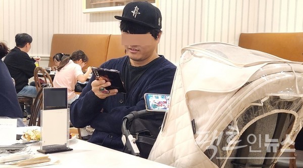 30대 부부가 두세 살 남아를 유모차에 태우고 식당에 왔다. 엄마가 음식을 가지러 간 사이 아빠와 아이가 스마트 전화기 삼매경에 빠졌다. 이 아이는 식당에 들어올 때부터 스마트 전화기에 푹 빠졌다. [사진=정수남 기자]