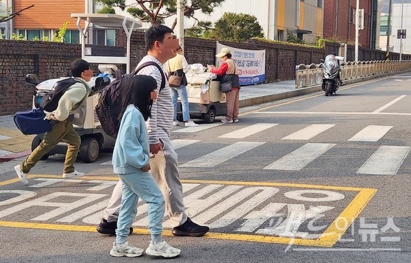 두 명의 야쿠르트아줌마가 횡단보도에 전동카드를 정차하고 제품을 팔고 있다. 이곳은 장애인 보호구역으로, 전동카드 옆 담 너머가 장애인 재활원이다. [사진=정수남 기자]