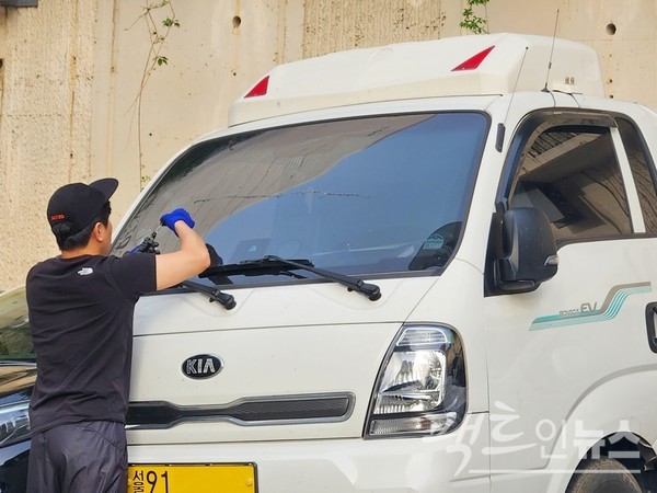 상업용 1톤 운전자가 차량 앞 유리에 금이 가자, 약품을 바르고 있다. 앞 유리 갈라짐이 더 확산하는 것을 방지하기 위해서다. [사진= 정수남 기자]