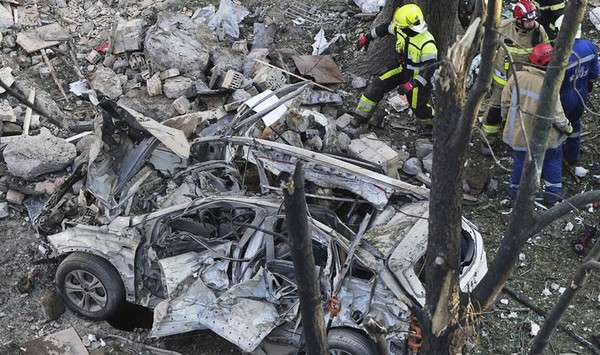  23일(현지 시간) 우크라이나 키이우에서 소방관들이 러시아의 공격으로 발생한 화재를 진화하는 현장에 파괴된 차량 잔해가 남아 있는 모습. [사진=뉴시스]