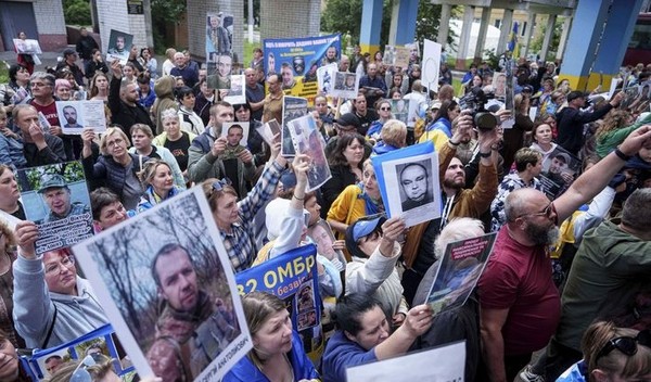 지난 6월 26일 러시아와의 포로 교환으로 석방된 우크라이나 군인들이 우크라이나의 체르느히우에 도착한 가운데 주민들이 실종된 가족의 사진을 들고 있다. [사진=뉴시스]